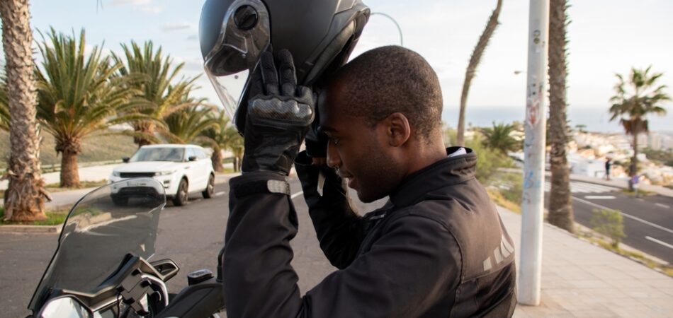 Smiling,african,american,biker,putting,on,full,face,helmet.,road